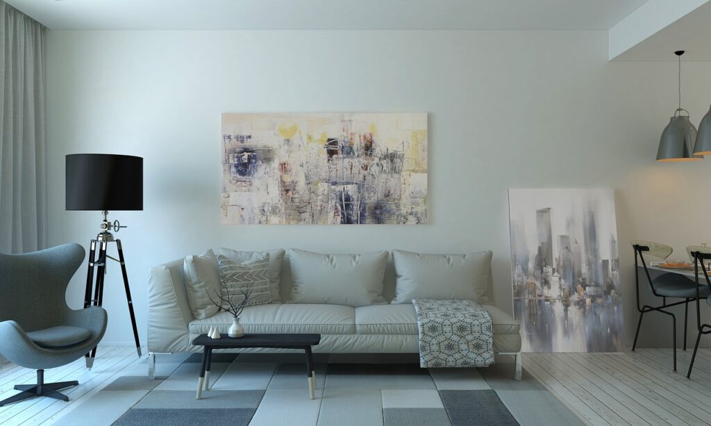 A modern, stylish living room featuring a light-colored sofa, abstract artwork, and chic furniture.